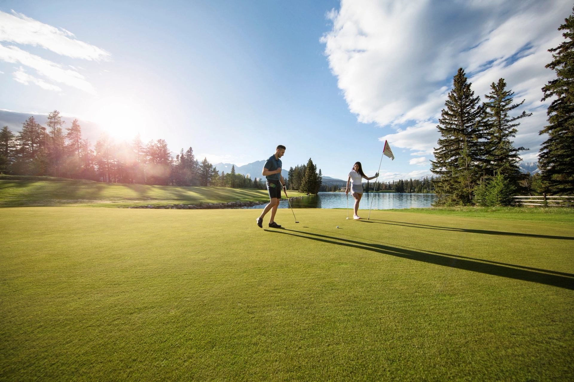 A man and woman golf at the Fairmont Jasper Park Lodge golf course.