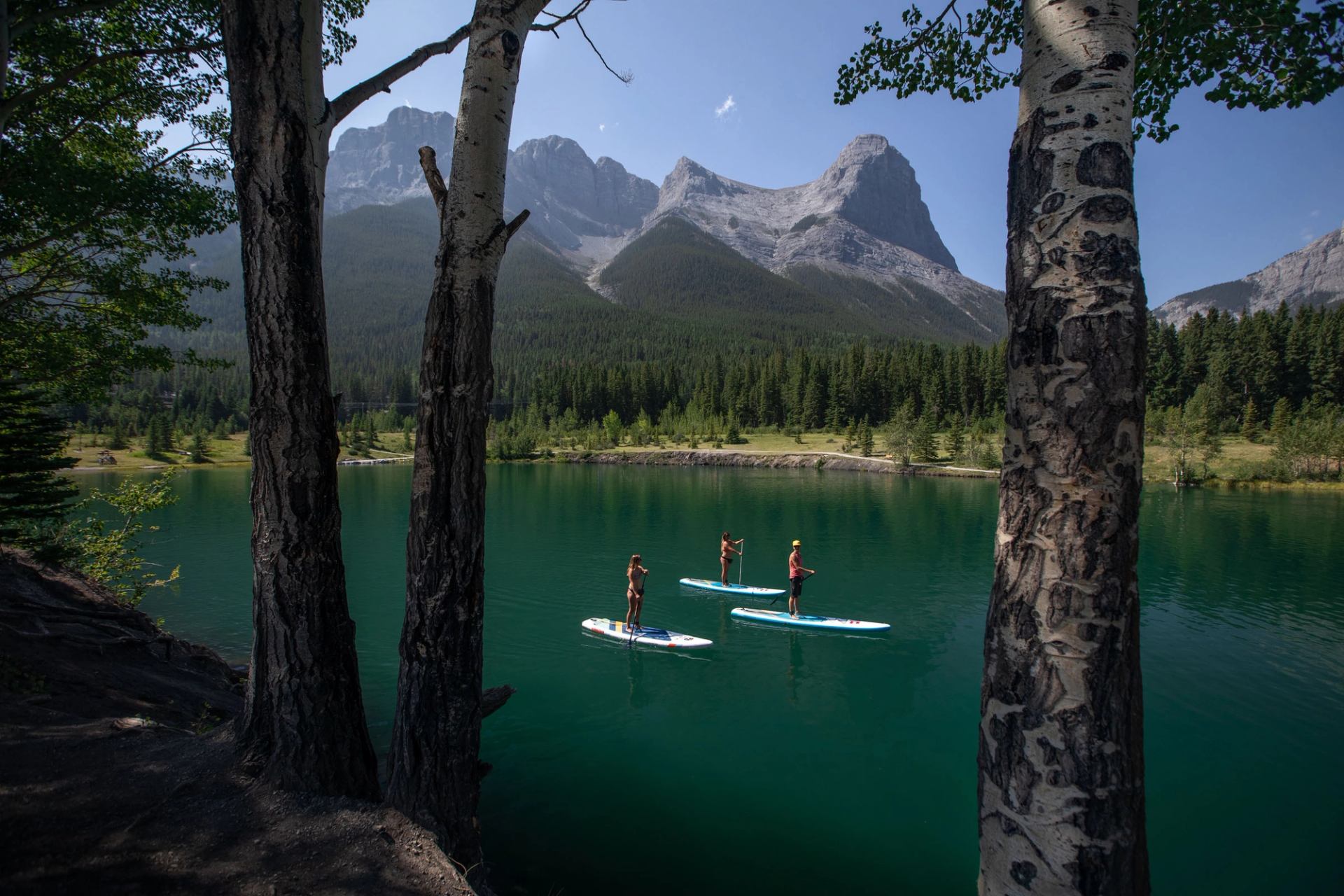 Three people explore the waters of Quarry Lake on stand-up paddleboards.