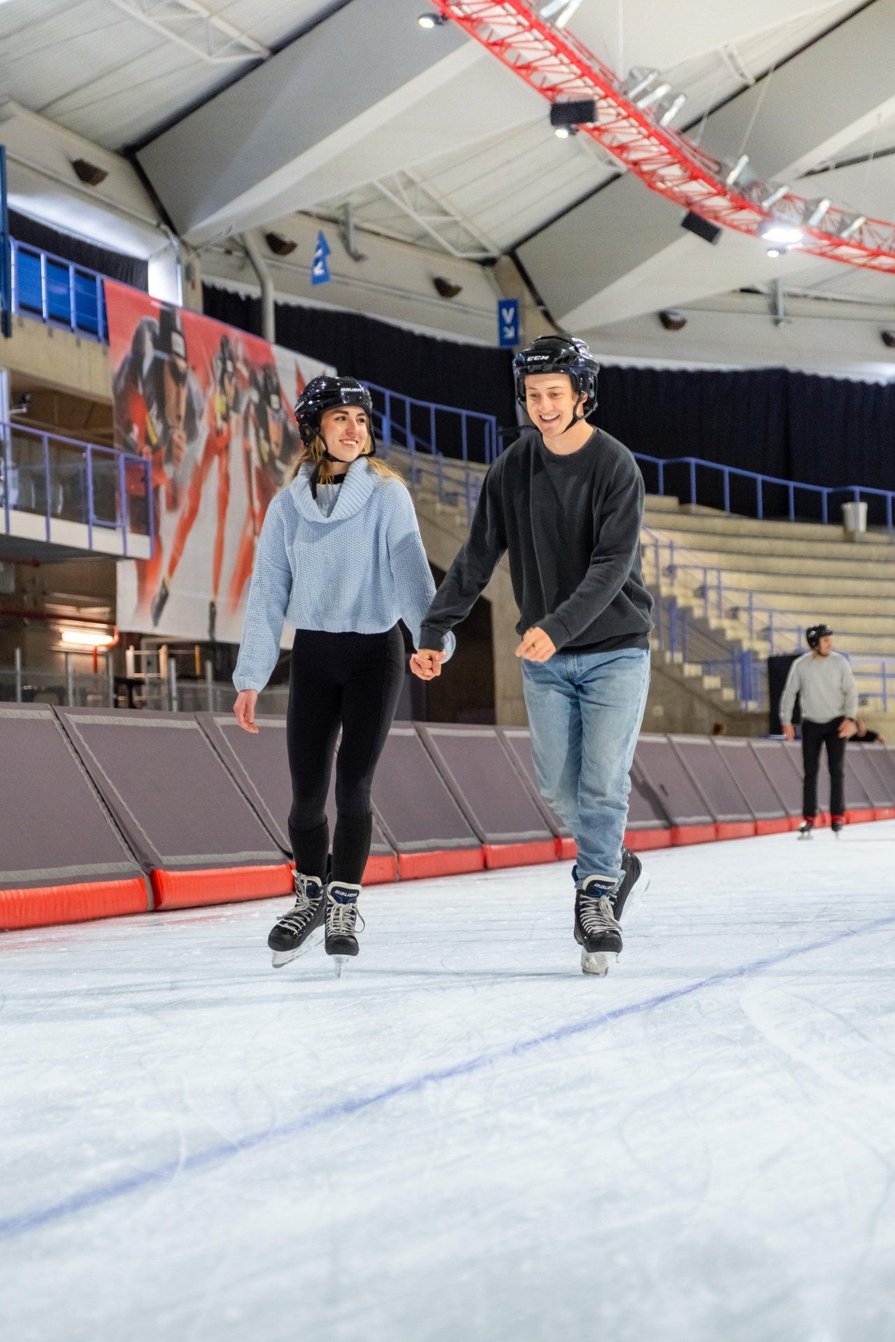 Two people hold hands while skating on the Olympic Oval ice.