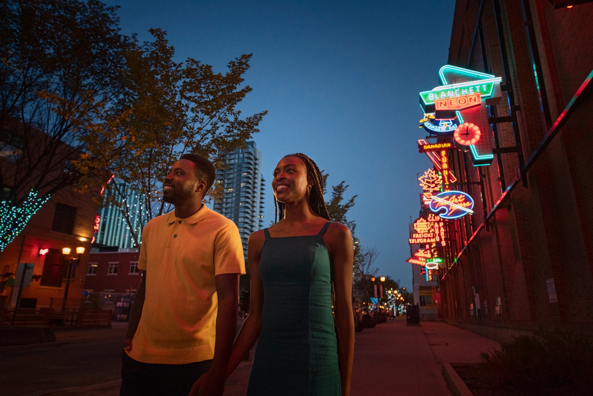 Couple walking through outdoor neon sign museum in Edmonton.