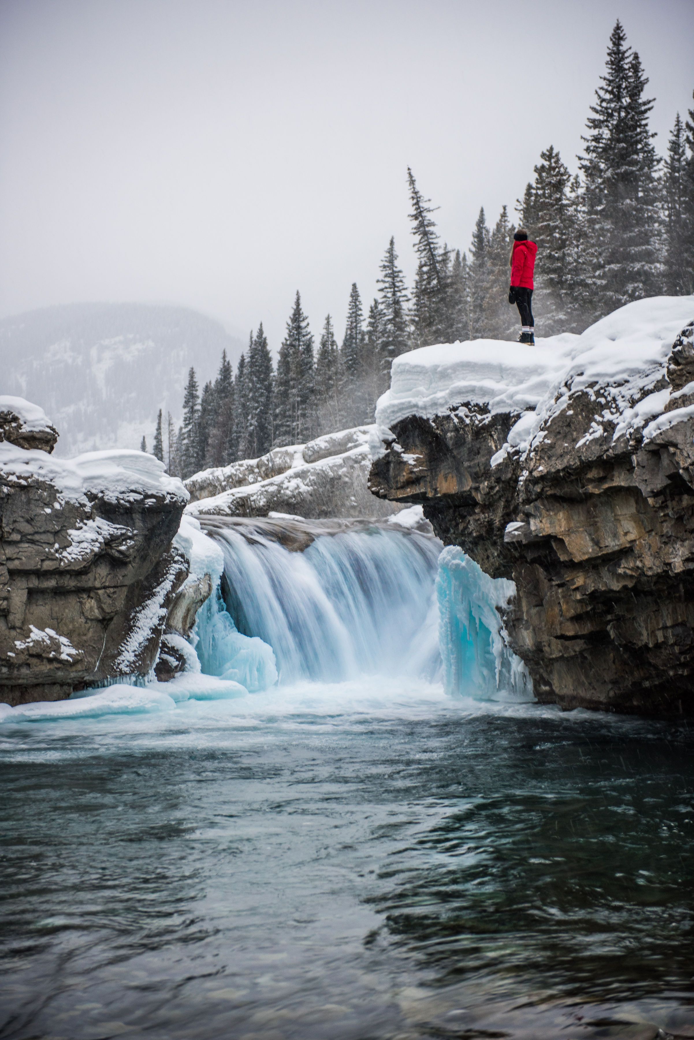 A person stands on a cliff overlooking the waterfall at Elbow Falls in Southern Alberta