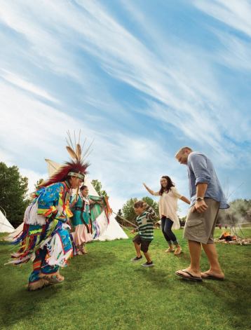 Family smiling and dancing with Indigenous dancers.