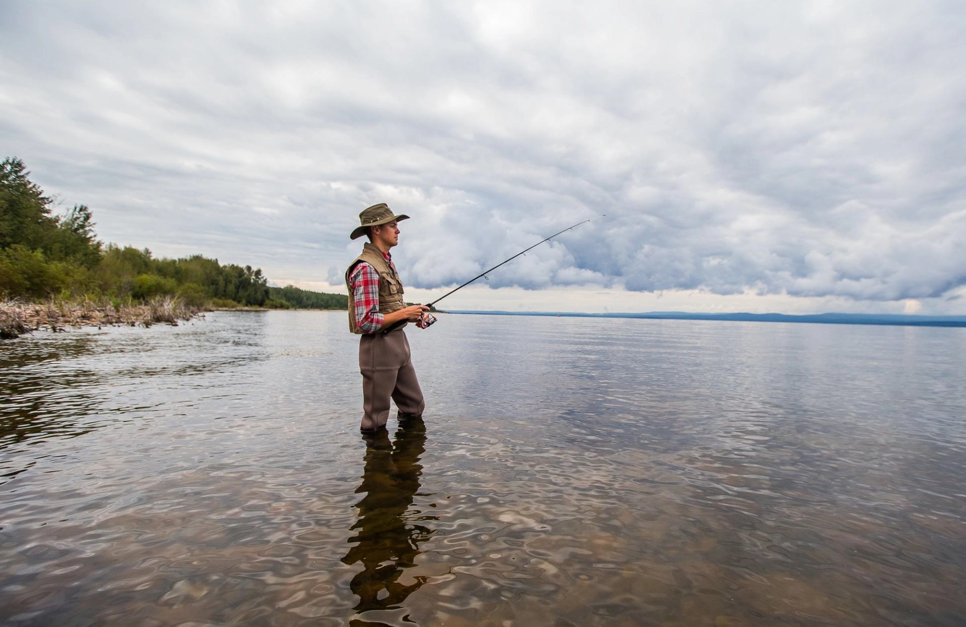 A man stands with fishing rod in Lesser Slave Lake