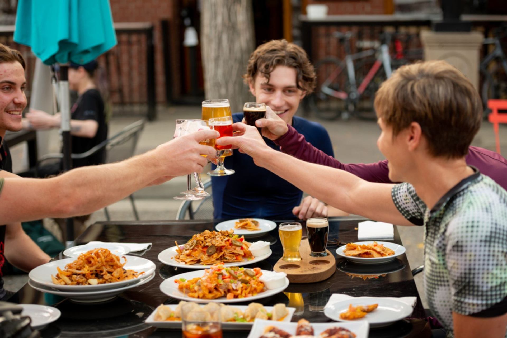 Group of friends raising glasses while having lunch on an outdoor patio.