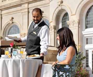 Two women being served lunch on an outdoor patio for a hotel restaurant.