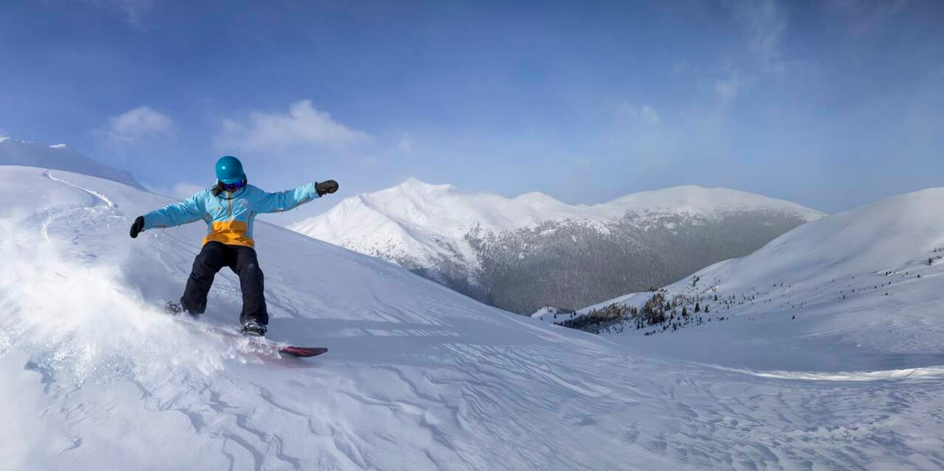 Snowboarder carves along snow atop Marmot Basin in Jasper
