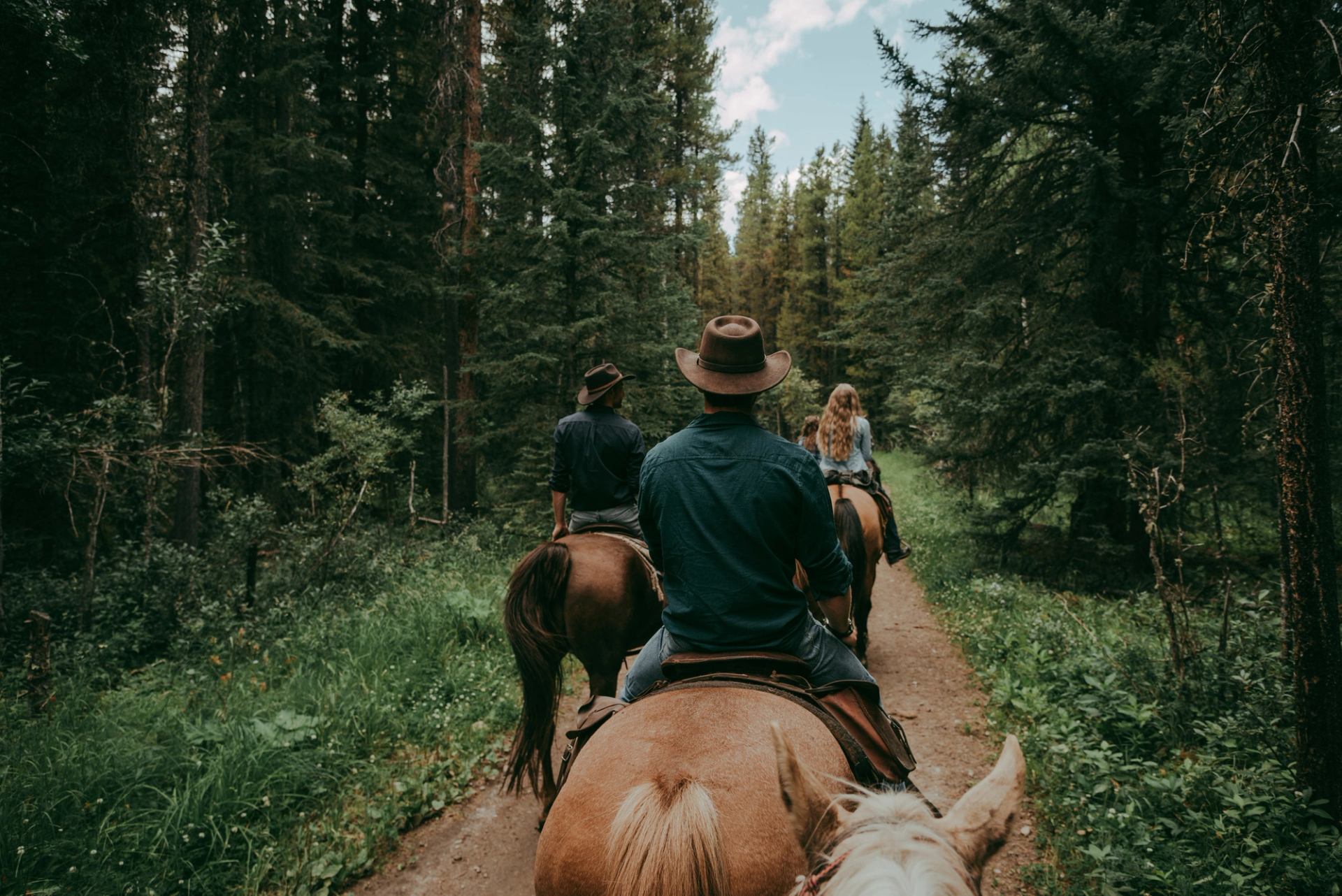 People horseback riding through the Rockies