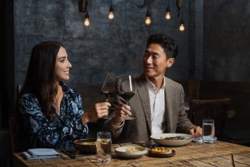 A couple clinks their wine glasses together in a cheers at RGE RD.