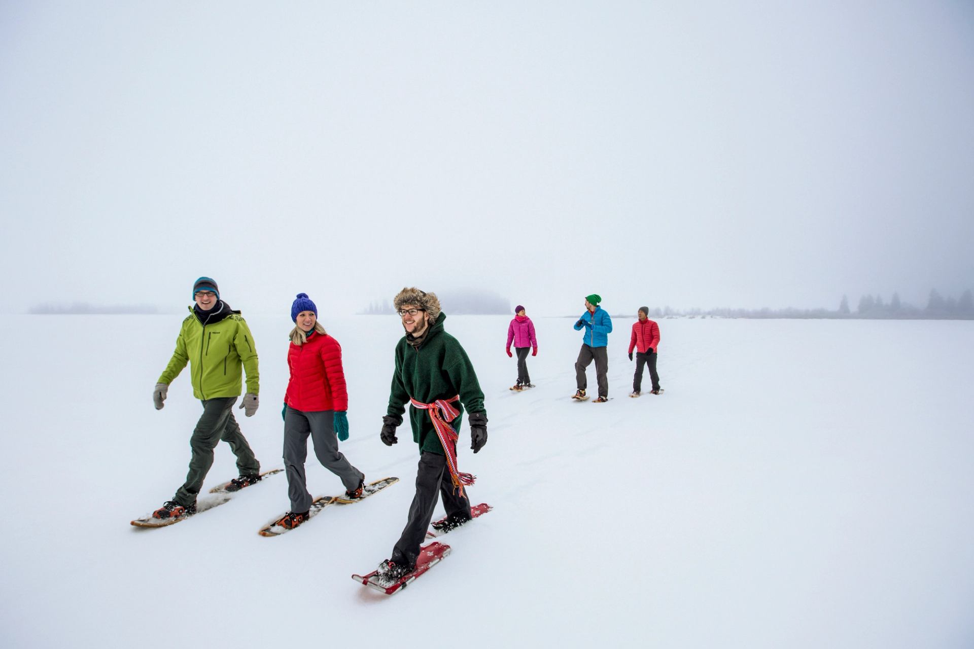 Friends snowshoeing with a guide across snowy Astotin Lake in Elk Island National Park.