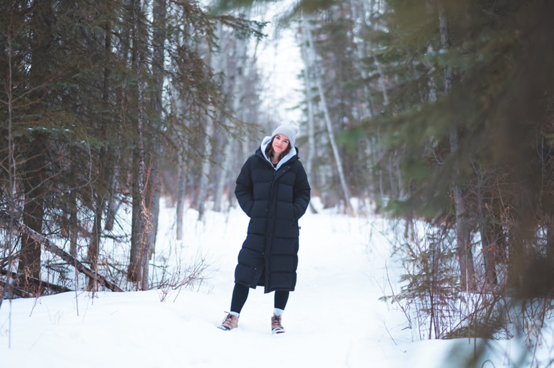 Woman standing in a snowy forest.