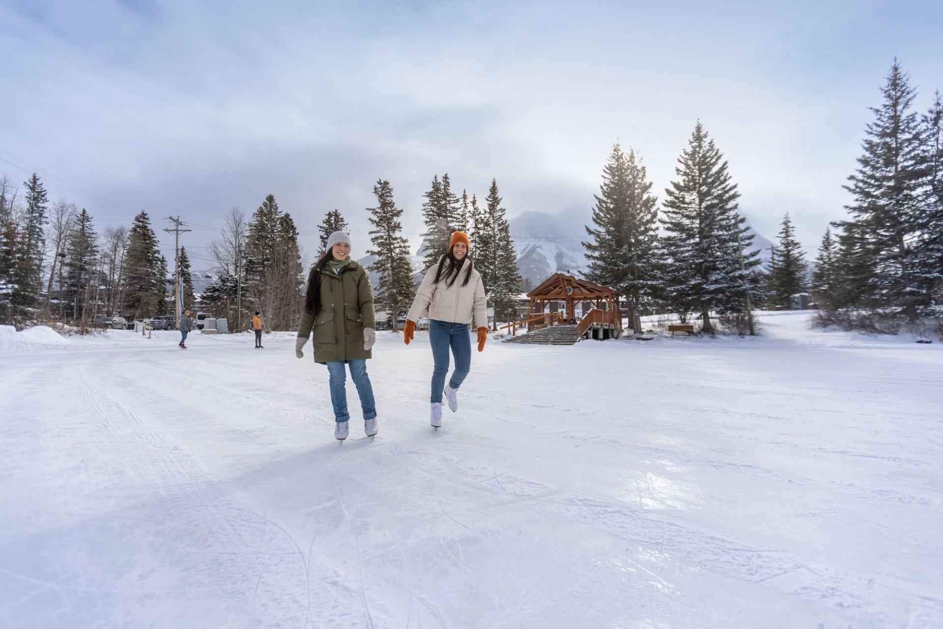 A group of friends ice skating on a frozen pond in Canmore.