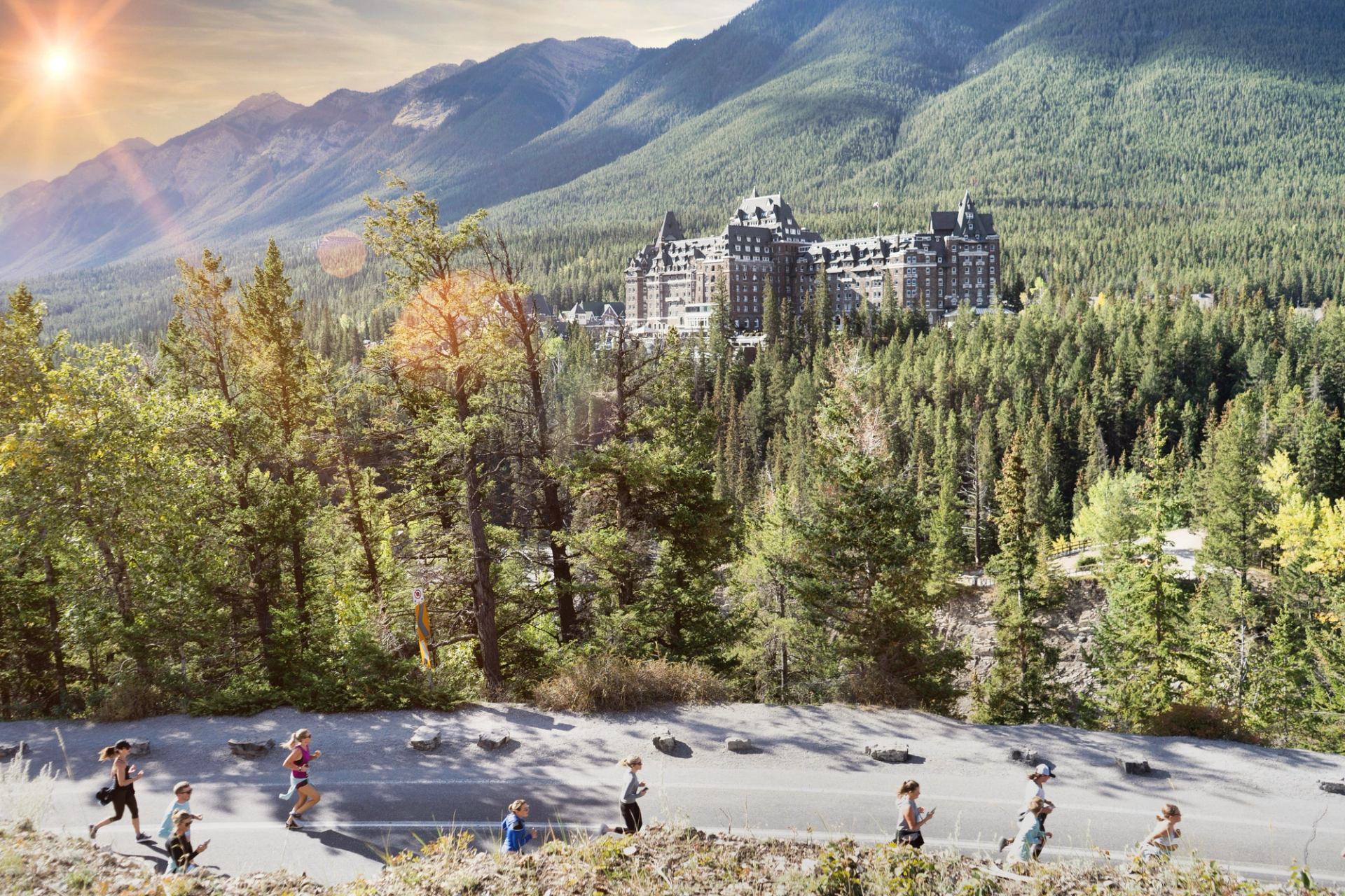 Runners run up the road past the iconic Fairmont Banff Springs Hotel and the Canadian Rockies.