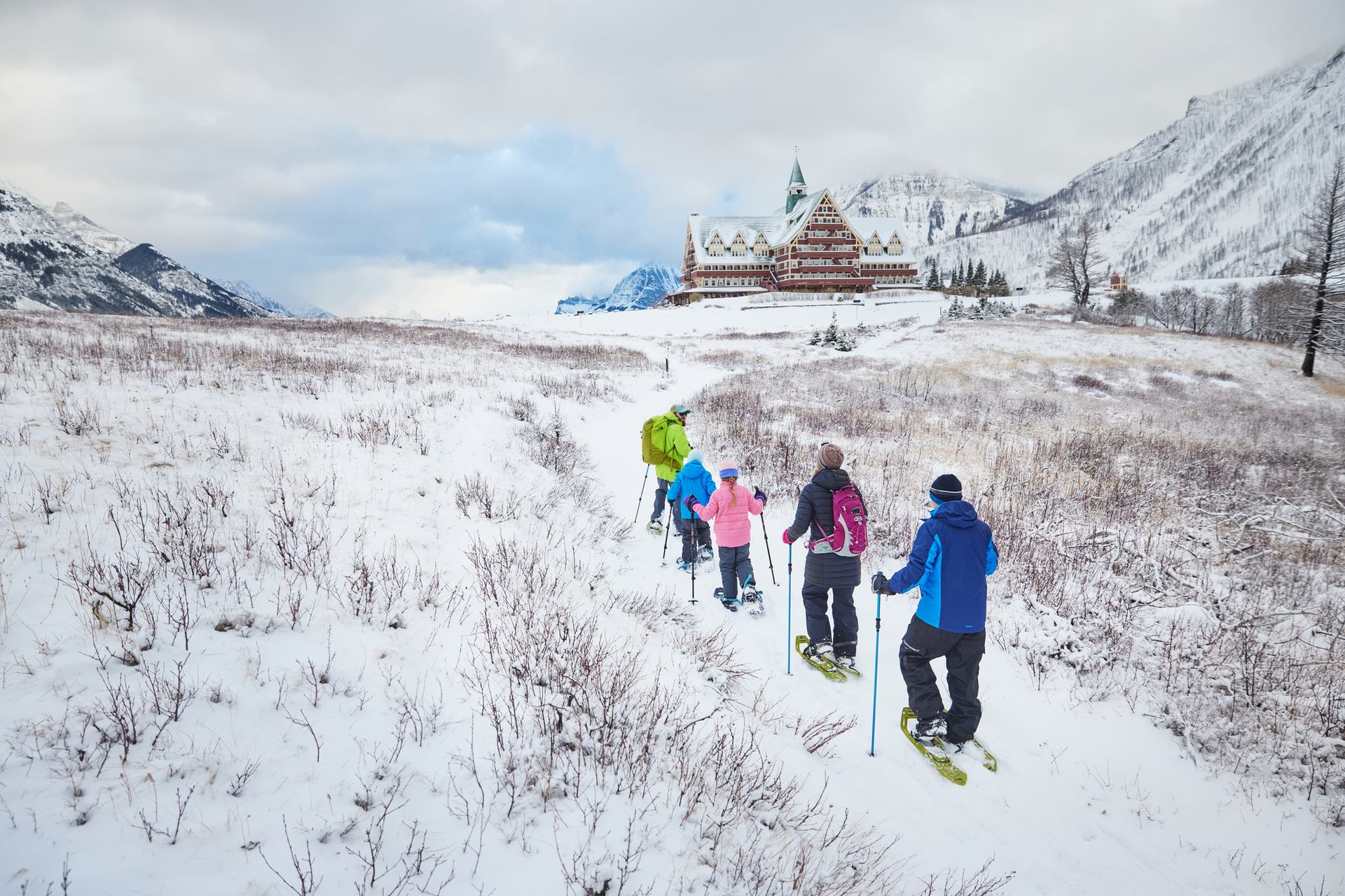 A group out snowshoeing with The Prince of Wales Hotel in the background.