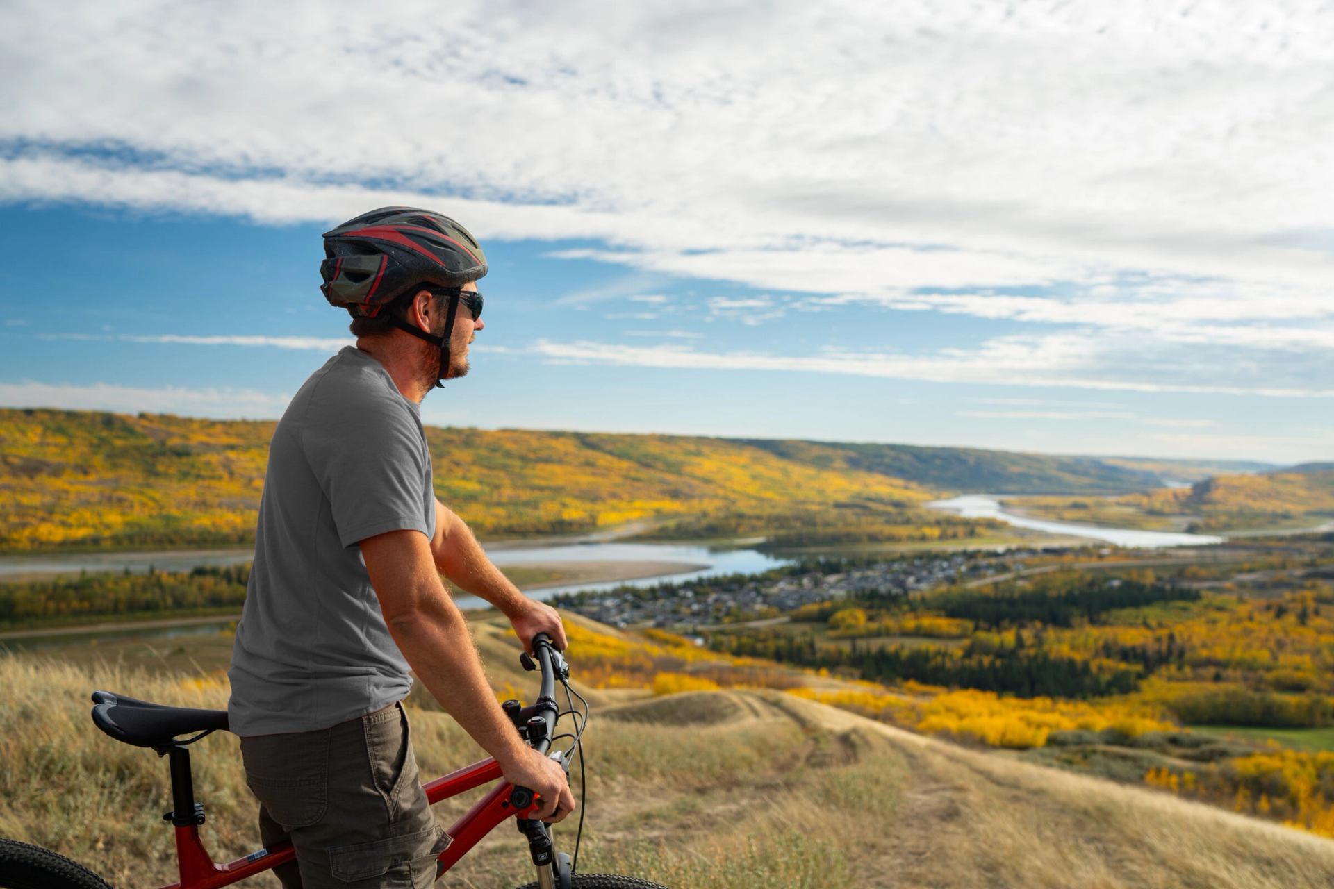 A mountain biker looks out over the fall colours of Peace River on top of Misery Mountain.