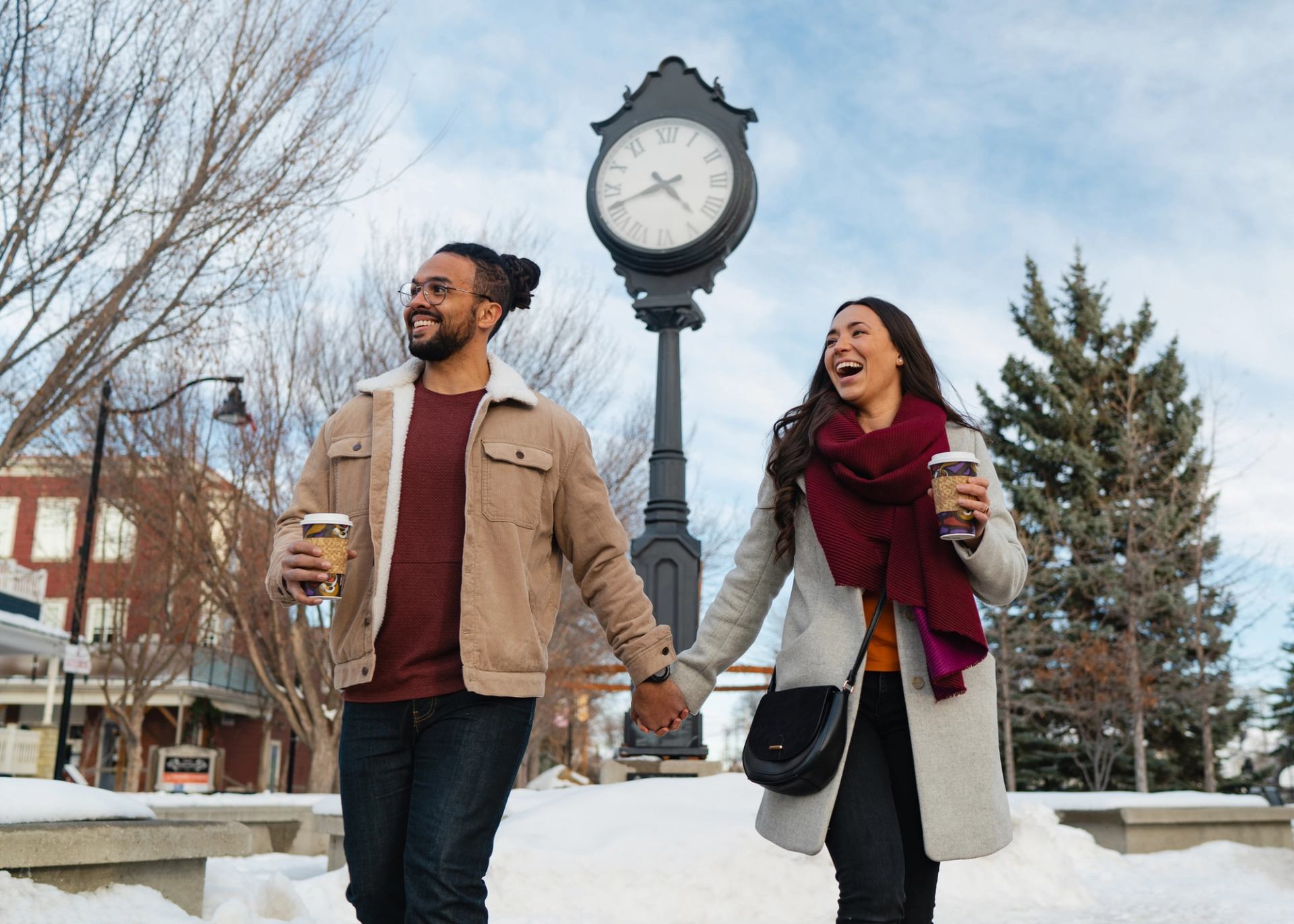 Couple walking with hot beverages in Old Towne Plaza in Okotoks.