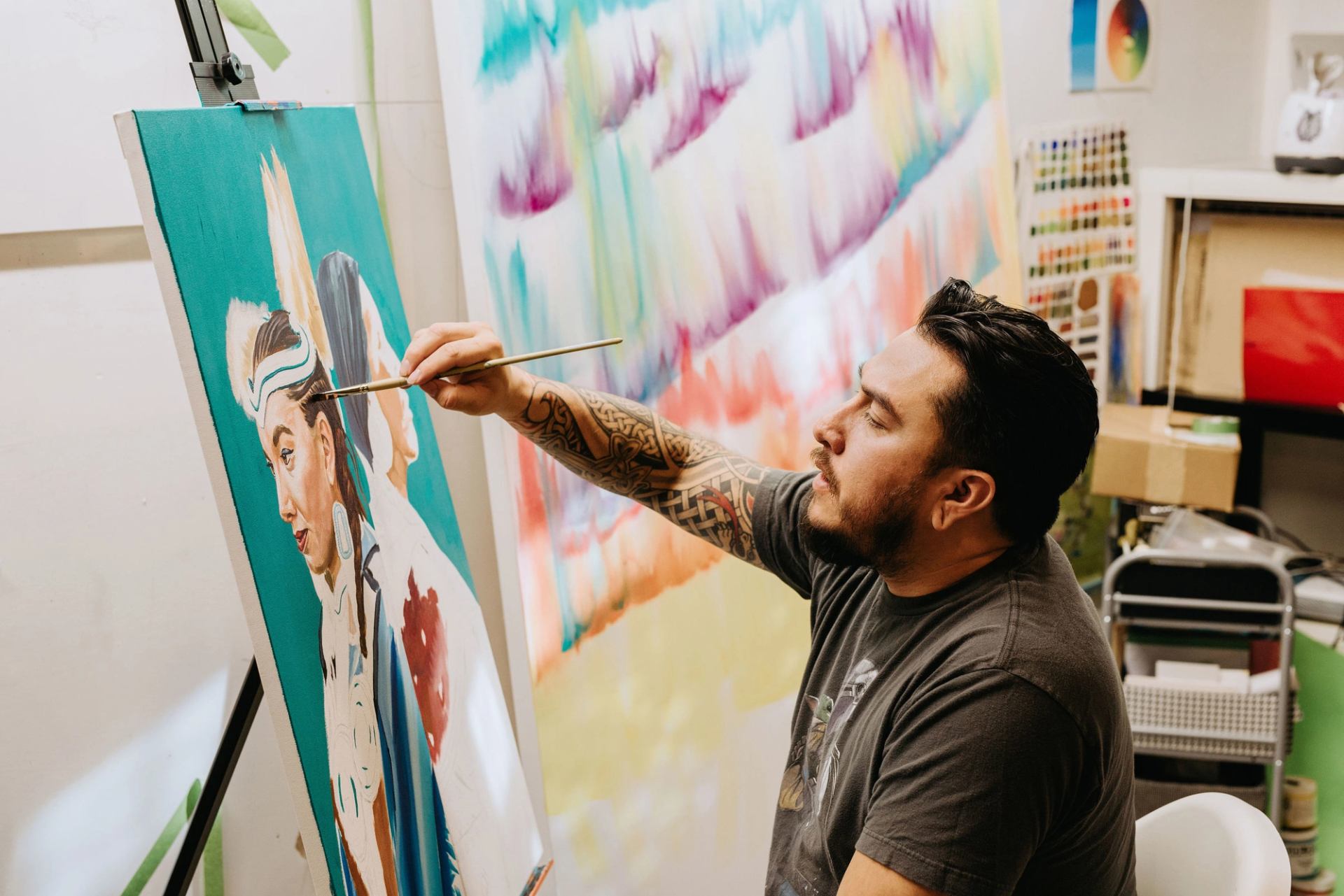 Indigenous artist Keegan Starlight painting on a canvas.