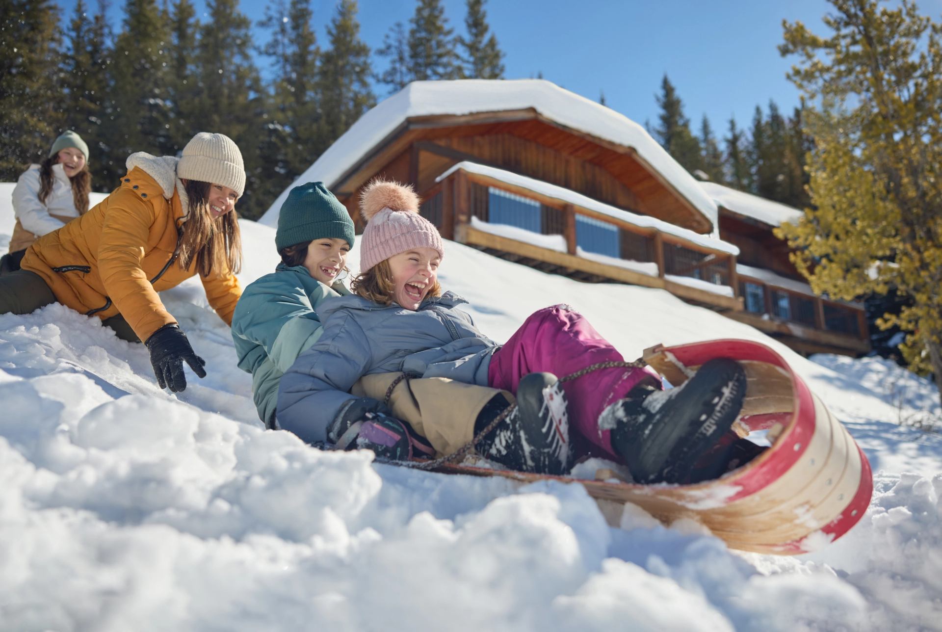 A group of children tobogganing down a snowy hill at Mount Engadine Lodge in Kananaskis.