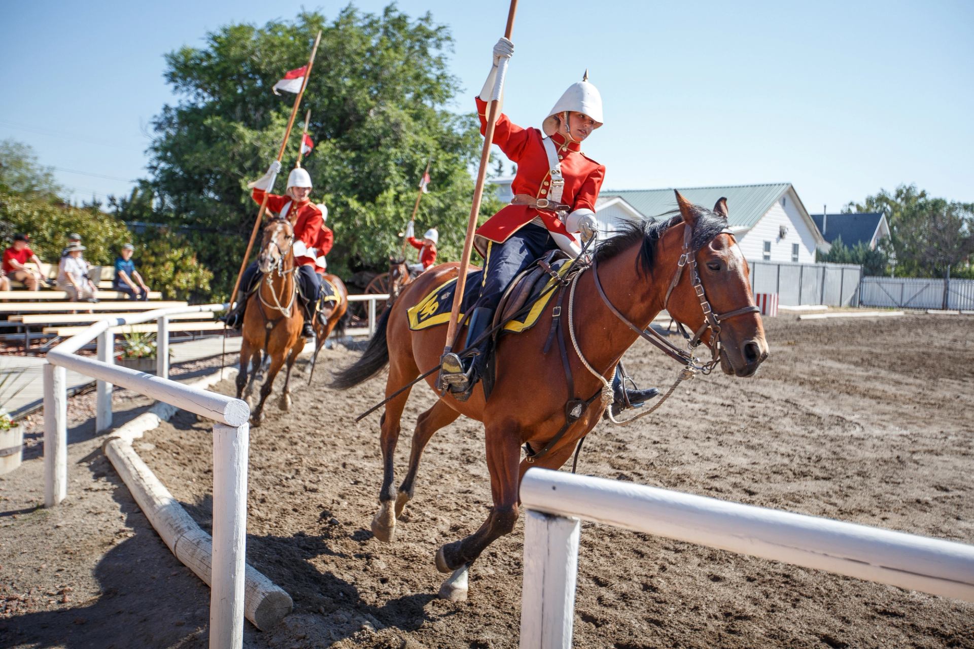 Interpreters dressed as 1870s Mounties ride horses and carry flags in the Musical Ride.