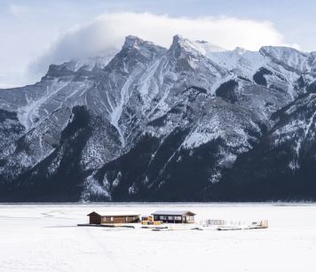 An ice fishing lodge/hut set up on the middle of a frozen Lake Minnewanka in Banff National Park