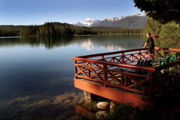 A man looking at Hector Lake at the Fairmont Jasper Park Lodge in Alberta