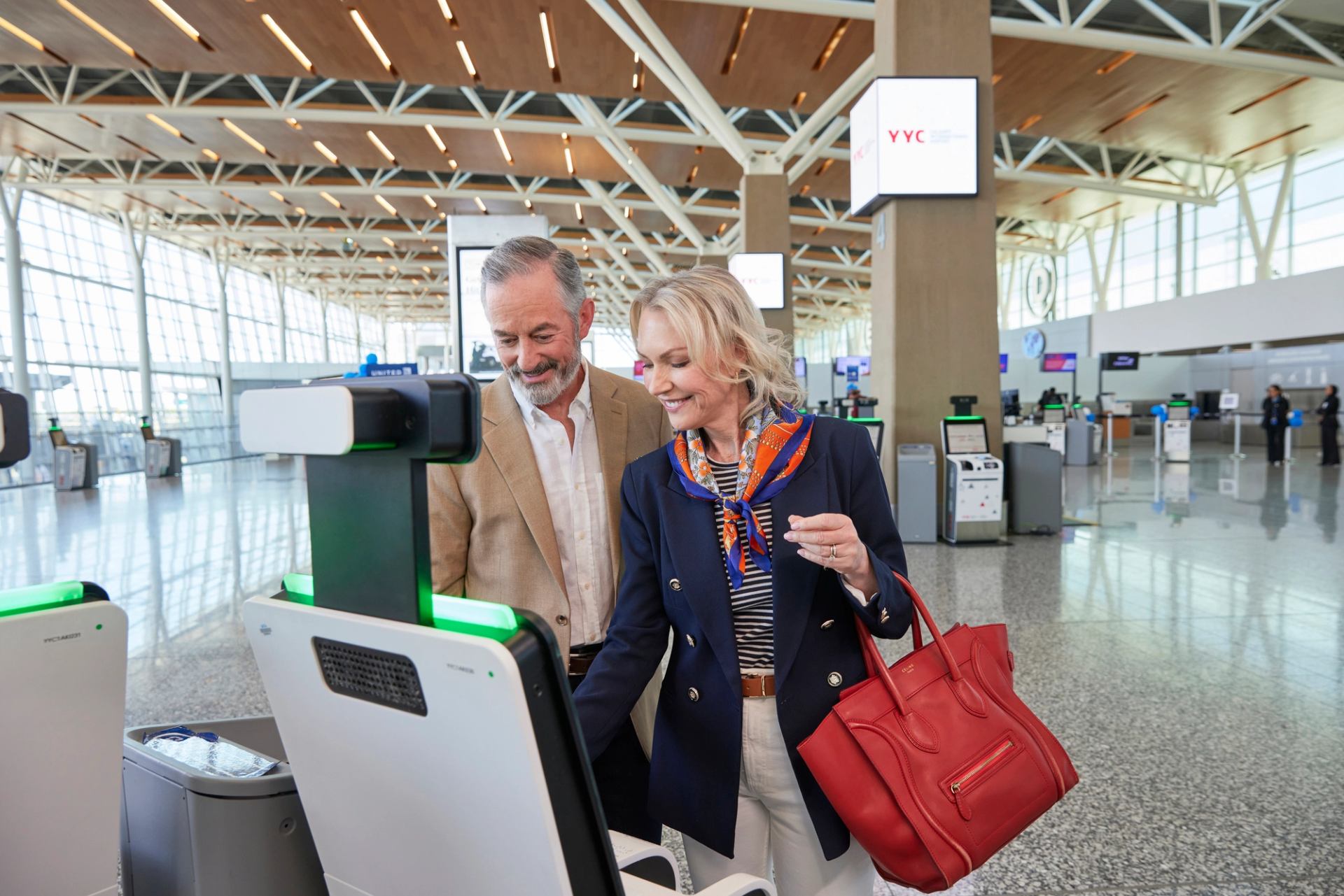 Two people check in at YYC Calgary International Airport using a digital kiosk.