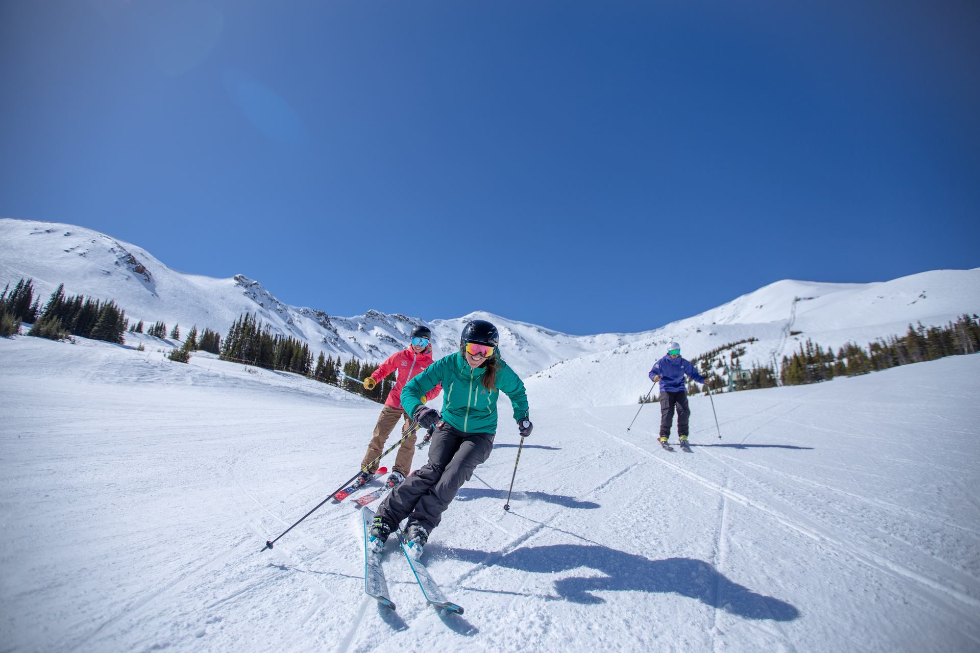 Three skiers front-on, skiing a groomed run at Marmot Basin in Jasper National Park