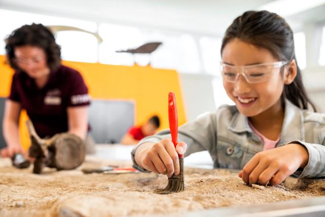 A young girl and a guide at the interactive fossil dig at the Royal Tyrrell Museum in Drumheller.