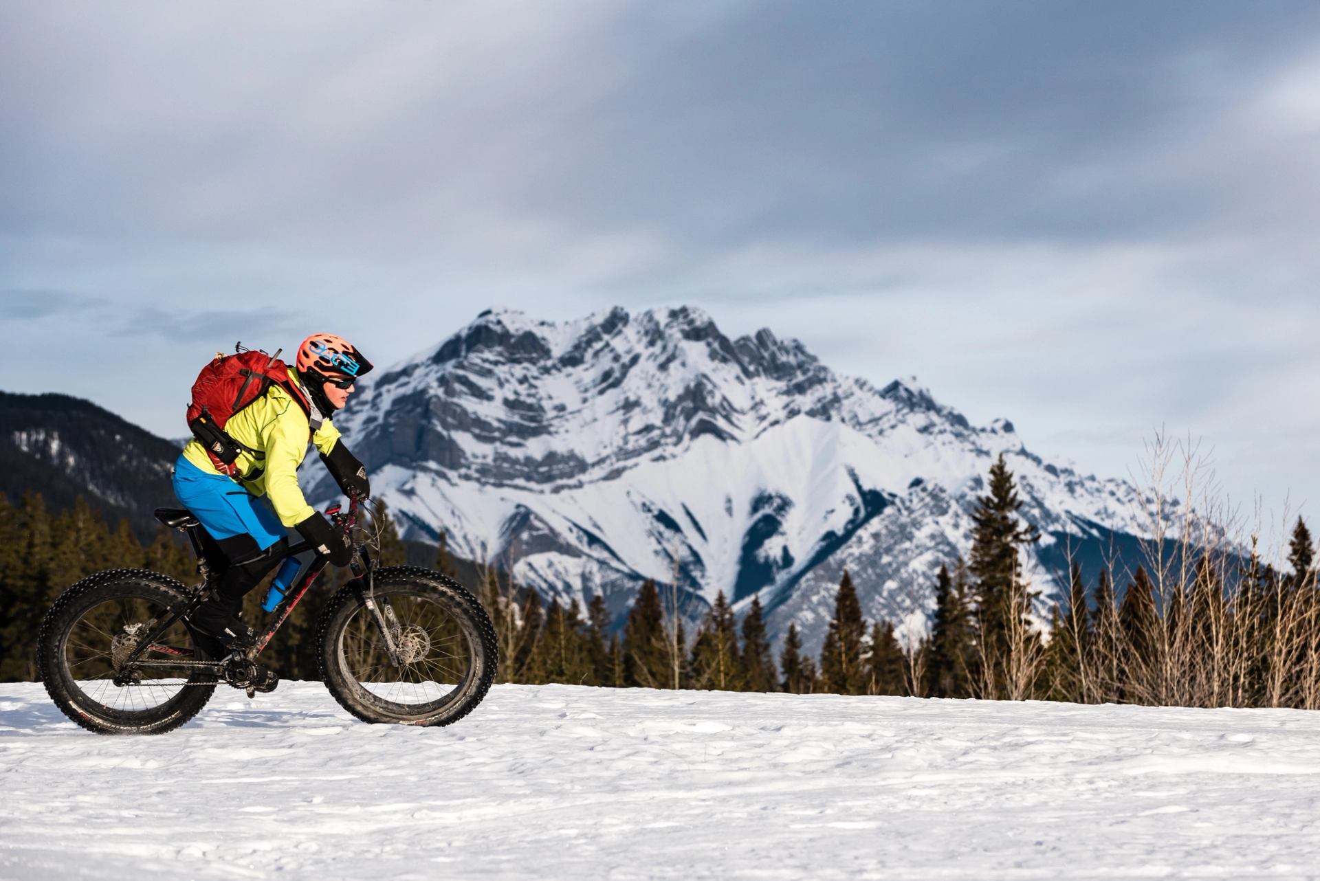 Person fatbiking in Canmore with mountains and blue sky in the background in Kananaskis Country