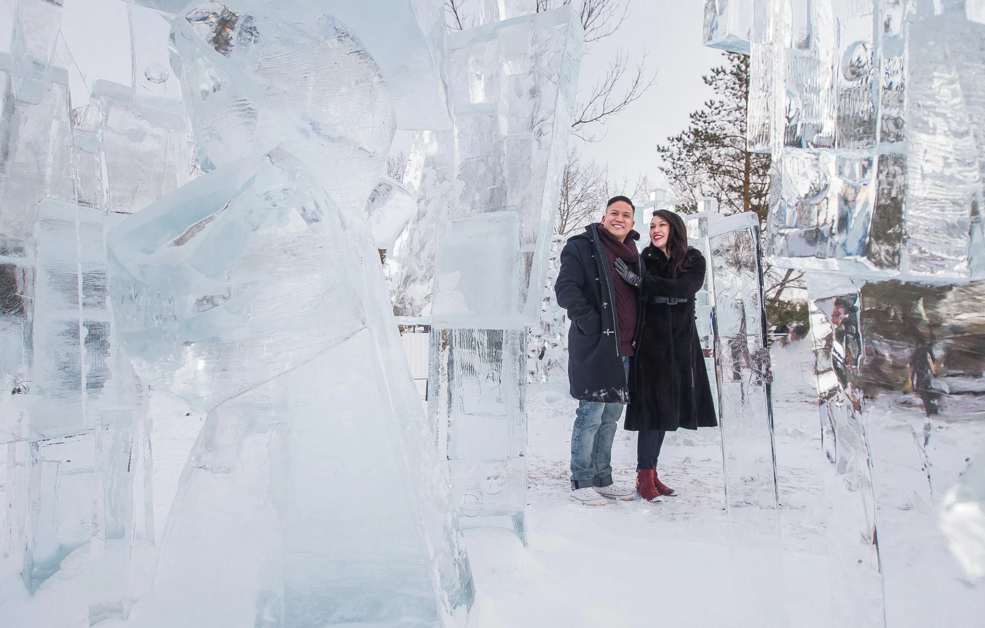 A couple walks through ice sculptures in a park.