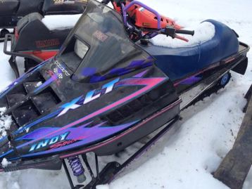 Parked snowmobiles in a parking lot.