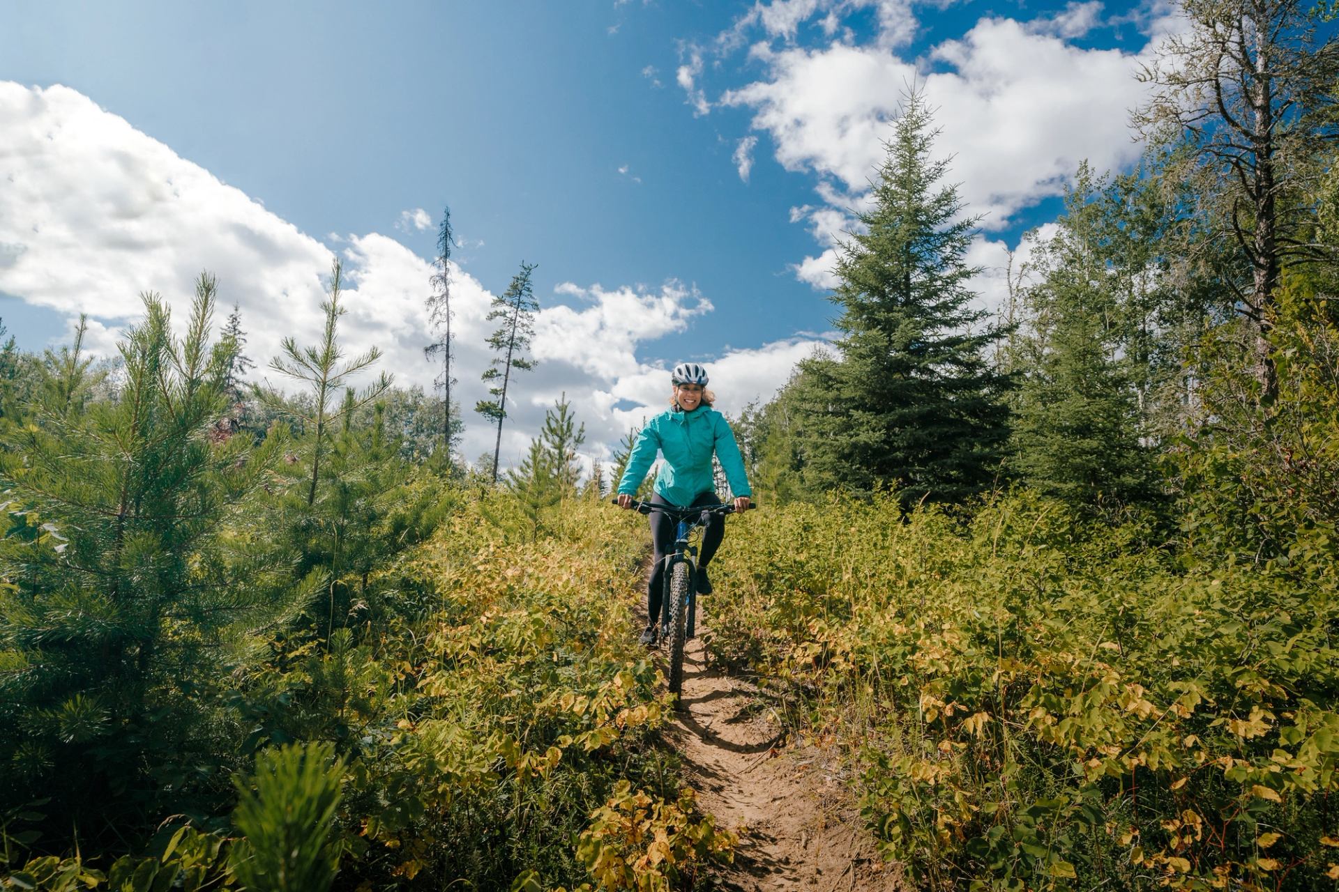 Person on a trail biking down a mountain at the Wapiti Nordic Centre.