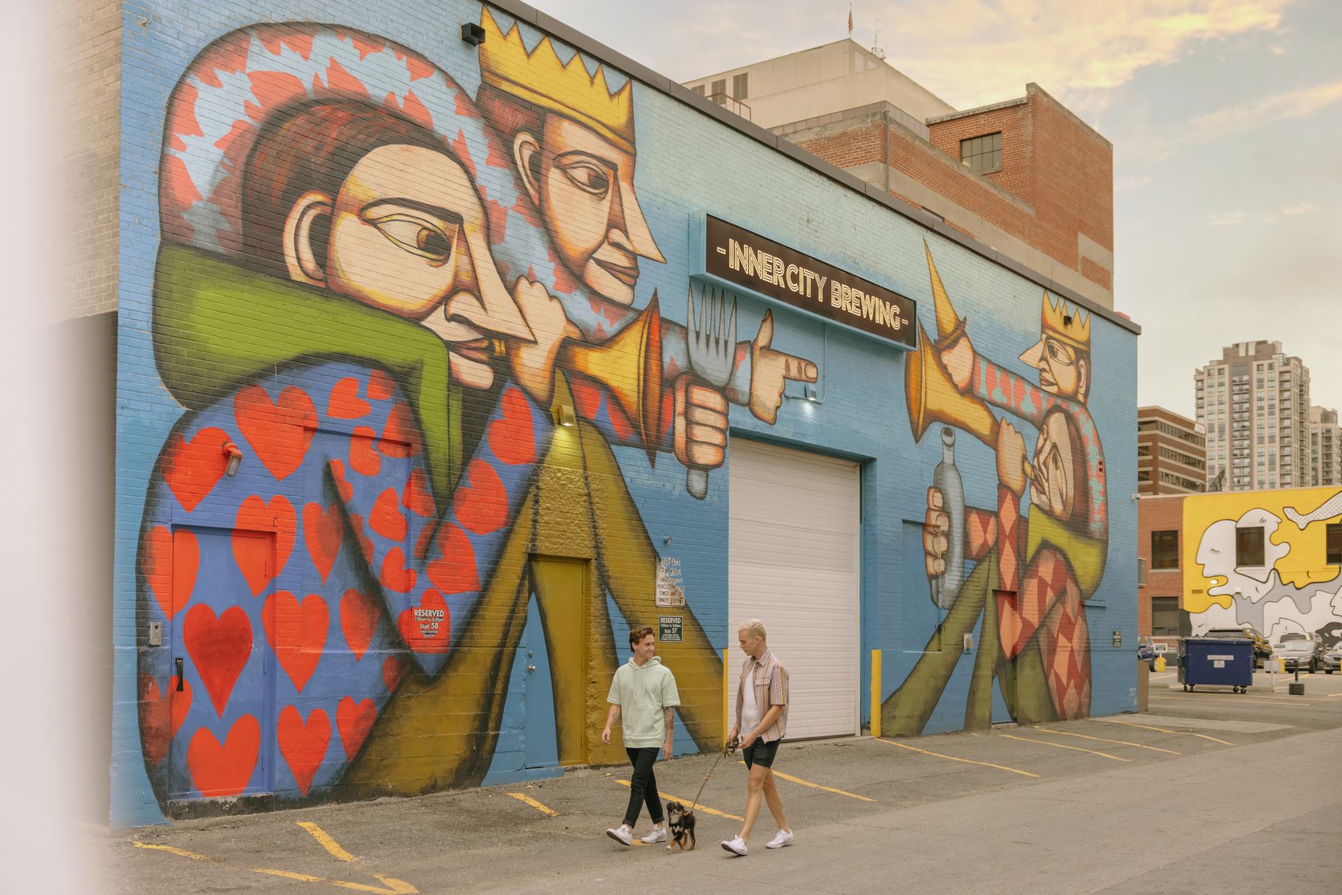 People walk in front of an art mural on a building in downtown Calgary.