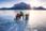 A guide shows visitors the ice bubbles at Abraham Lake with a mountain in the distance.