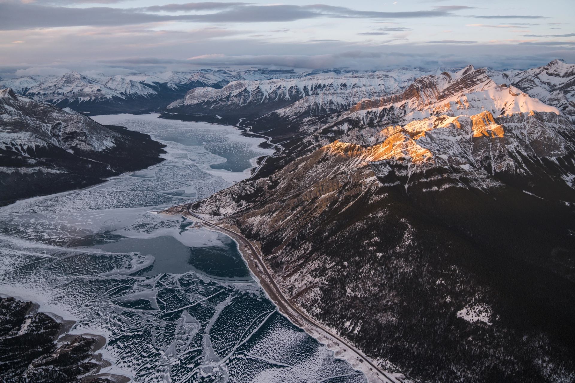 Aerial scenic shot of an icy lake surrounded by snow-capped mountains.