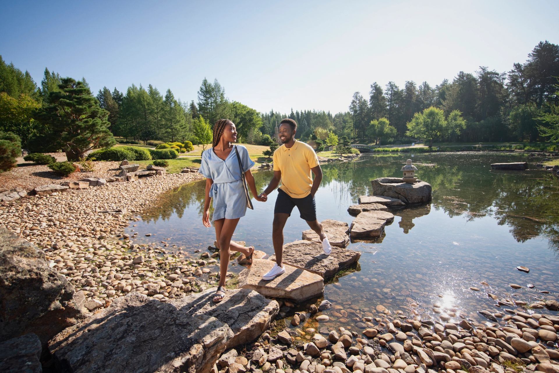 A couple hold hands while walking on rocks in the Botanical Gardens at the University of Alberta.