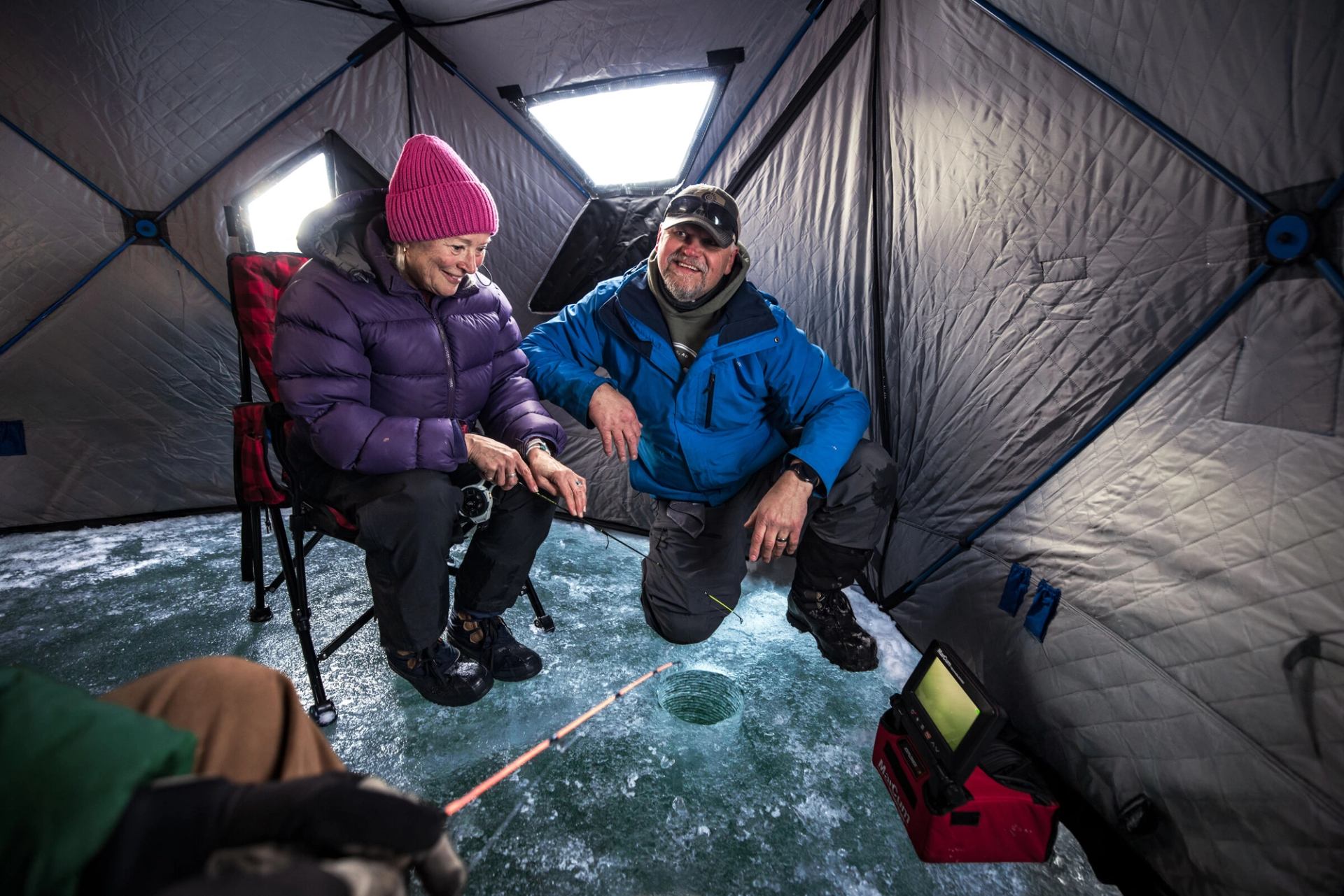 A woman with an ice fishing guide in a tent.