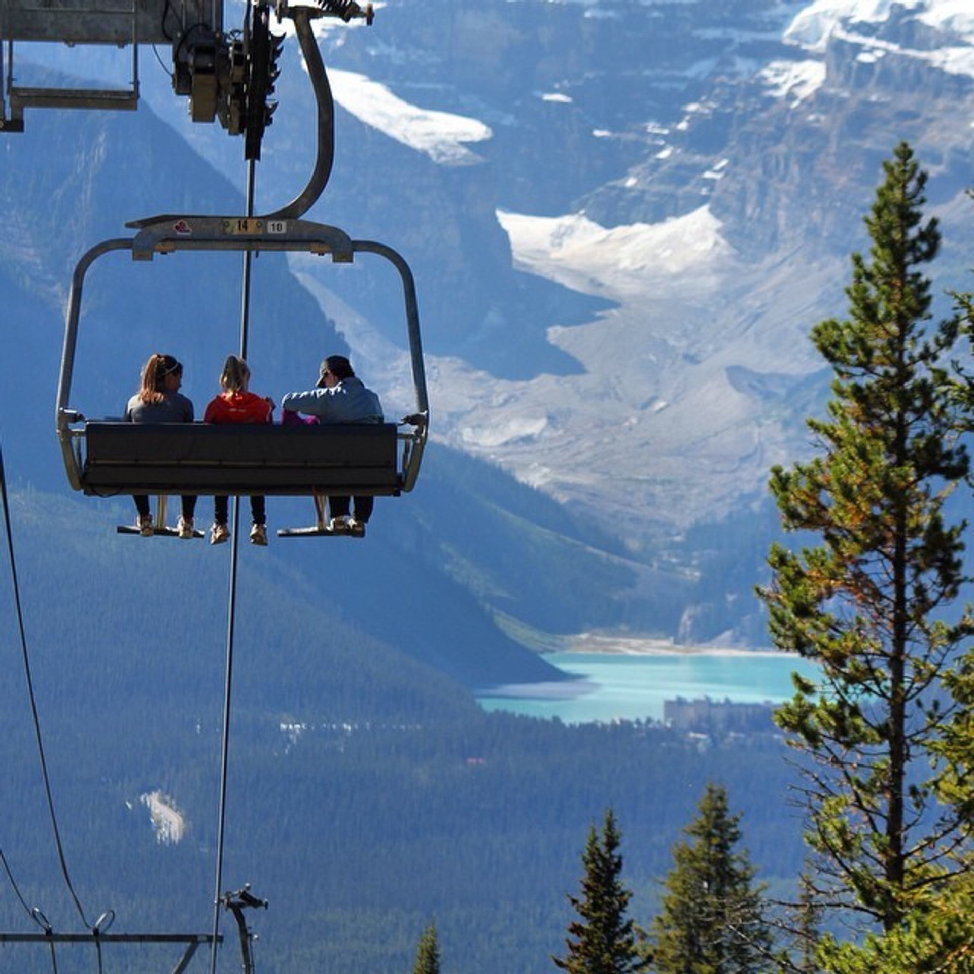 People on a chairlift with views of Victoria Glacier over Lake Louise in the summer in Banff National Park.