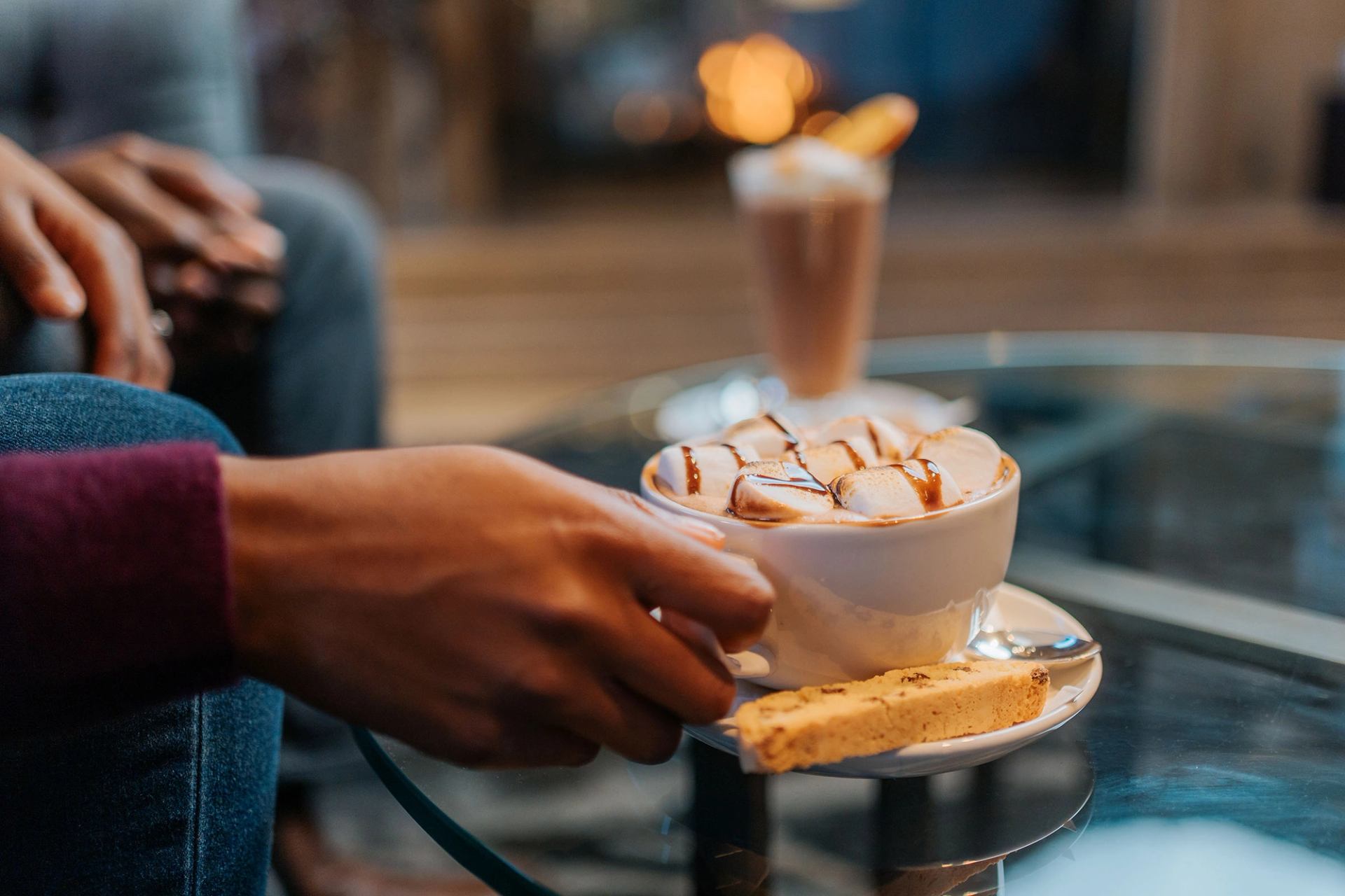 A hand picking up a mug of hot chocolate.