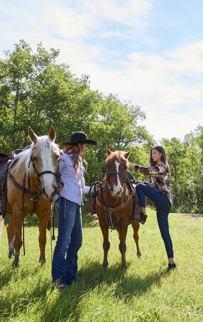 A couple get ready to mount and ride their horses while horseback riding at Heritage Ranch near Red Deer