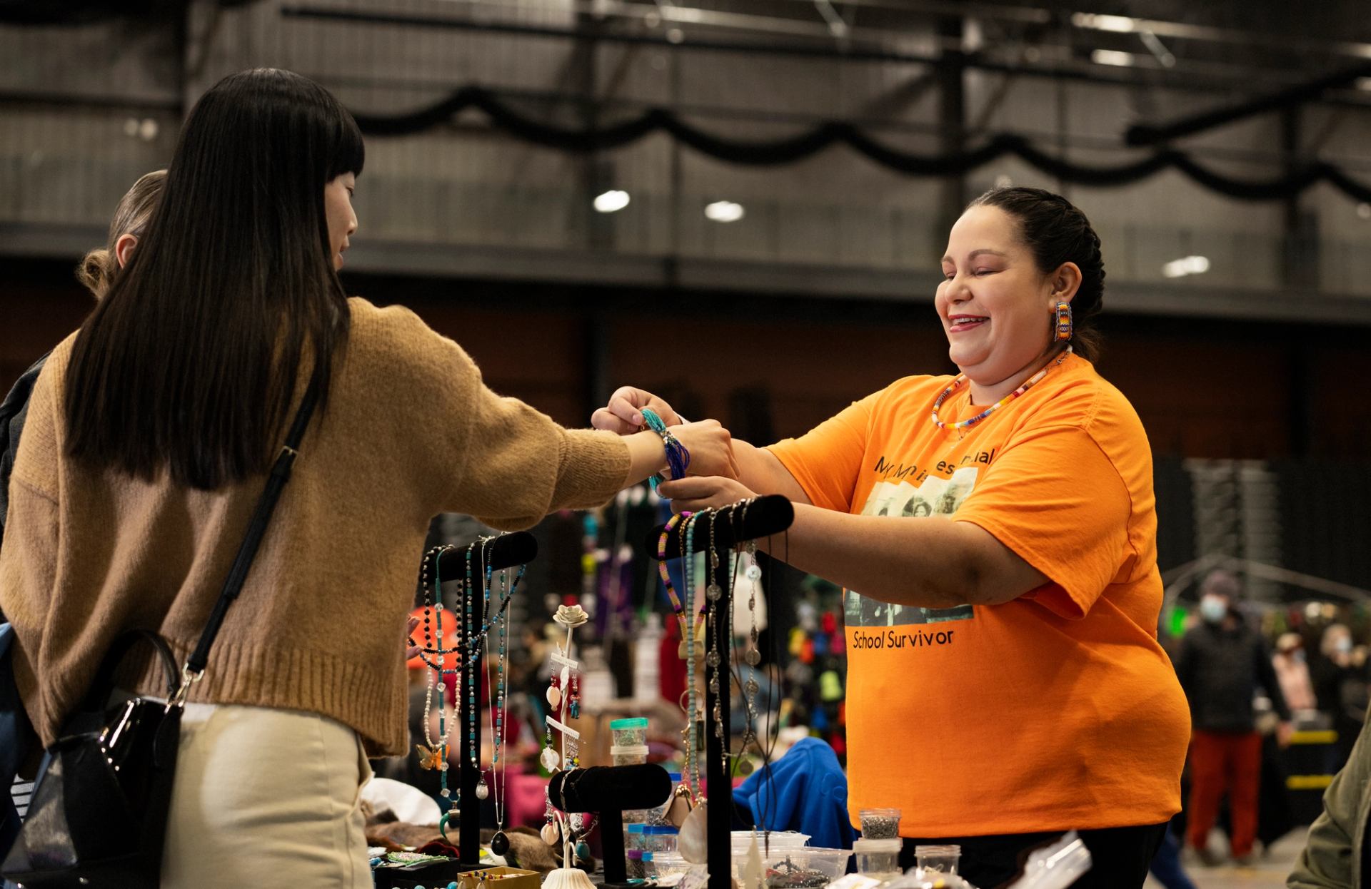 A vendor hands an item to a shopper at the Christmas at the Nation Holiday Market.