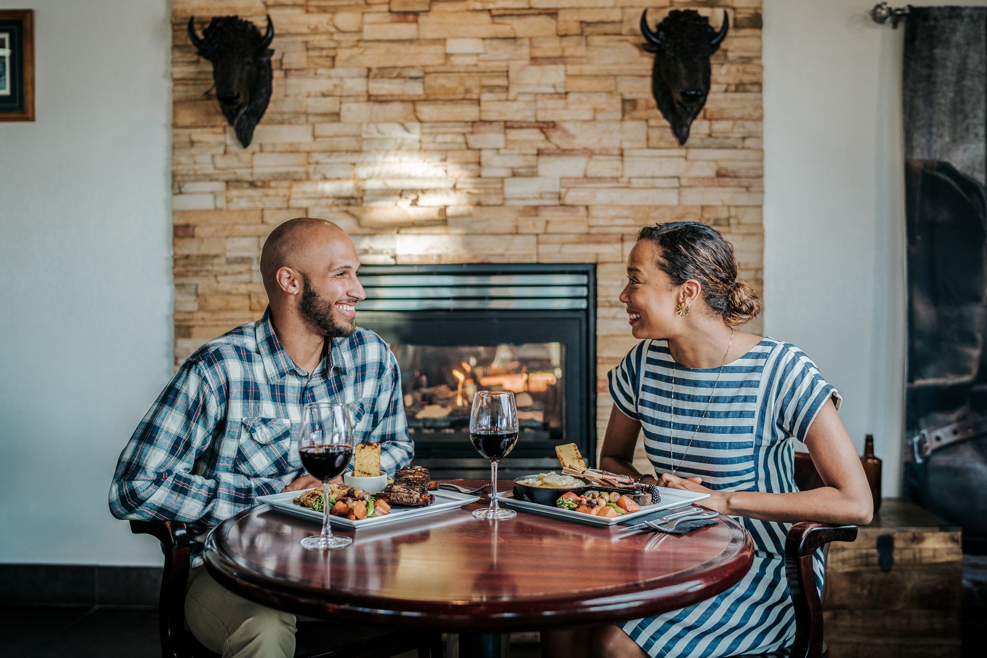 Two people sit at a table with dinner and wine at Frontier Eatery in Grande Prairie.