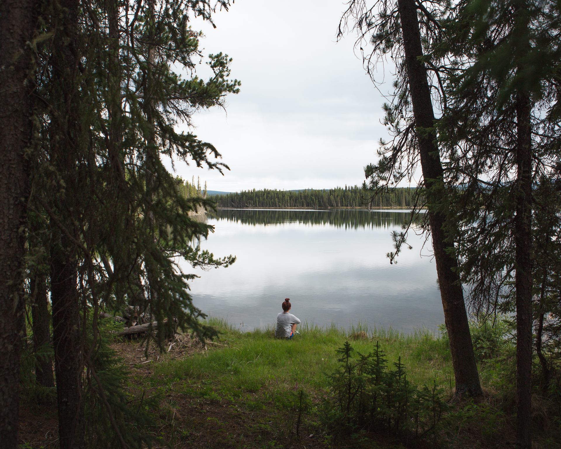 A woman sitting on the grass at Pierre Grey’s Lakes Provincial Park near Grande Cache.