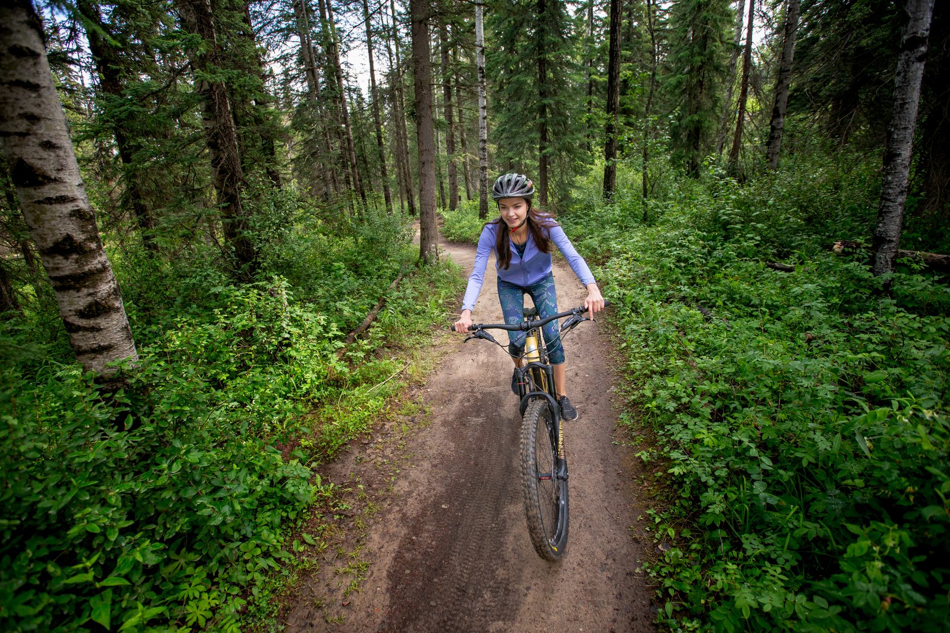 A woman rides a bike along a dirt track in the woods in Hinton.