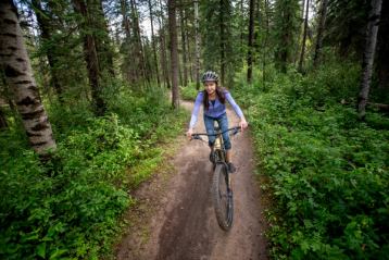 A woman rides a bike along a dirt track in the woods in Hinton.