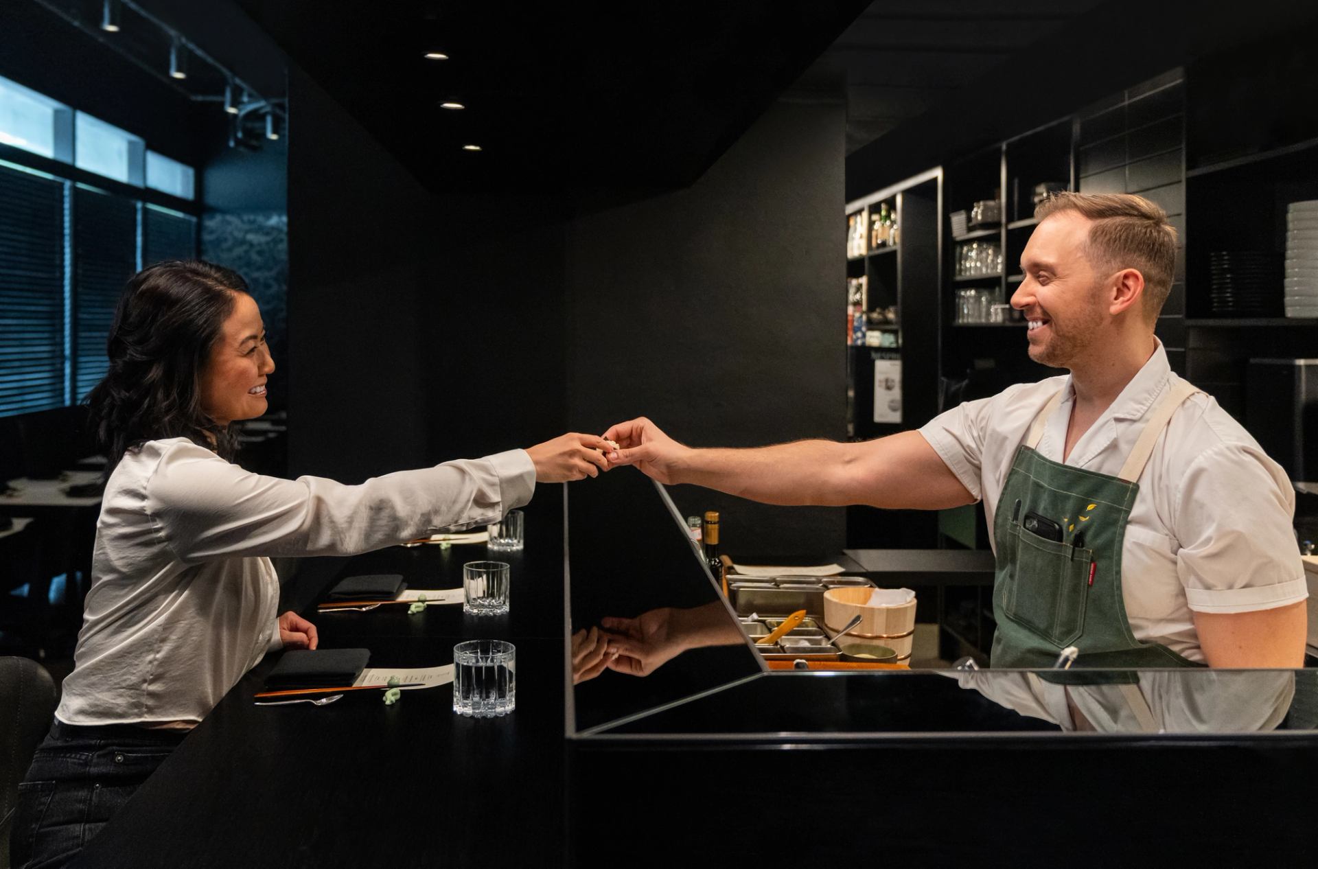 Chef Darren MacLean hands a guest some sushi over top of the counter at Nupo in Calgary.