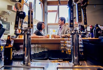 A couple having a beer at the bar of a brewery.