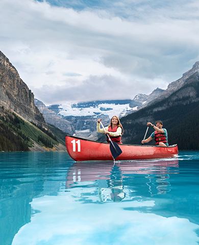 Young couple canoeing on Lake Louise on a sunny day. They are surrounded mountains. Making for a peaceful relaxing adventurous atmosphere.