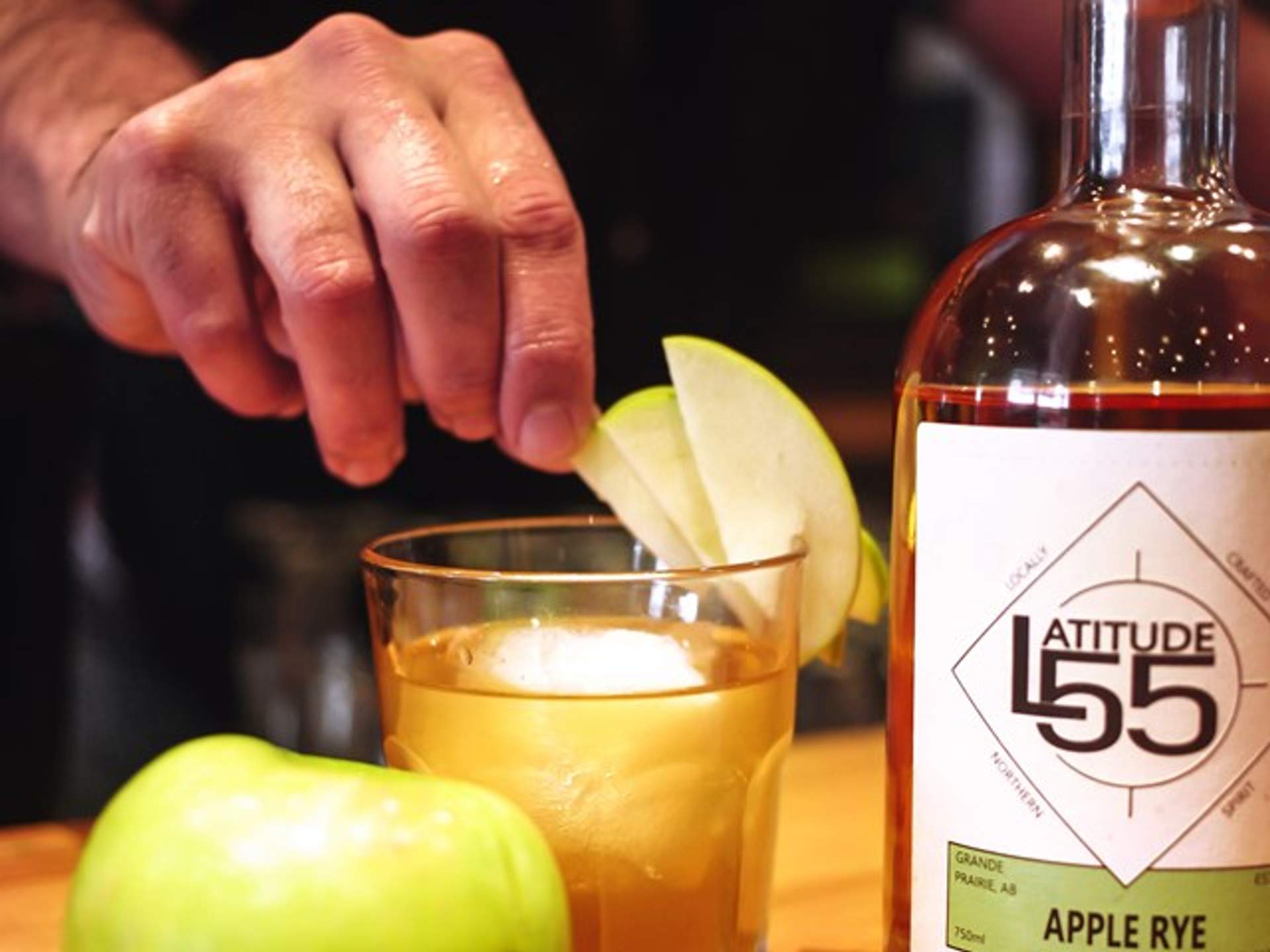 A bartender adding slices of apple to a drink