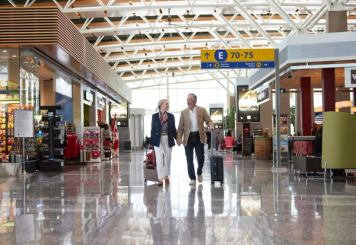 A couple walks through a terminal past shops and restaurants at Calgary International Airport.