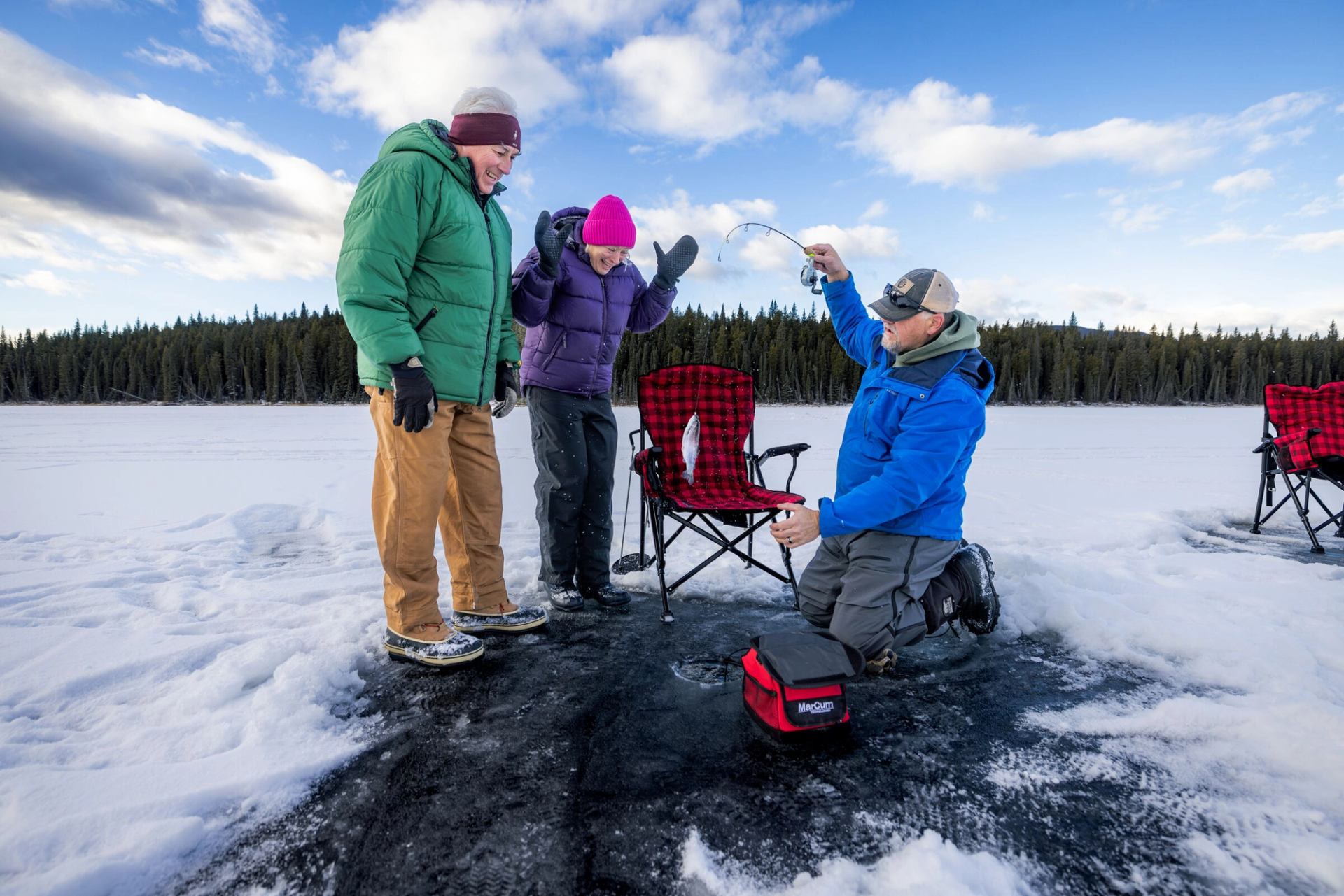 An ice fishing guide with a couple catching fish.